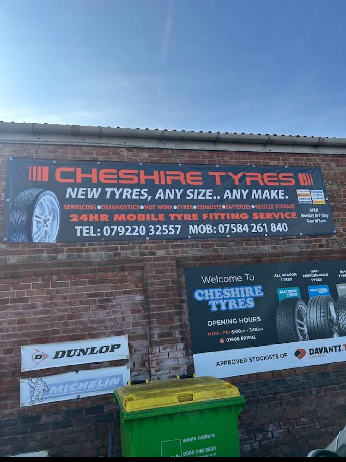 The Cheshire Tyres banner and welcome sign on the brick wall of the unit, listing servicing, diagnostics, MOT work, tyres, exhausts, batteries and vehicle storage