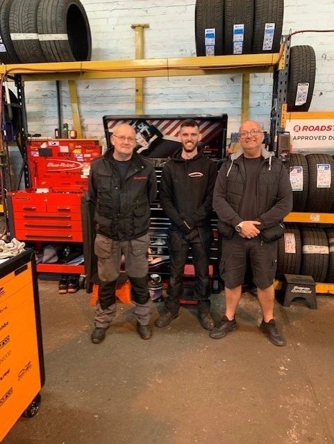 The Cheshire Tyres team in the workshop in front of the tyre racks